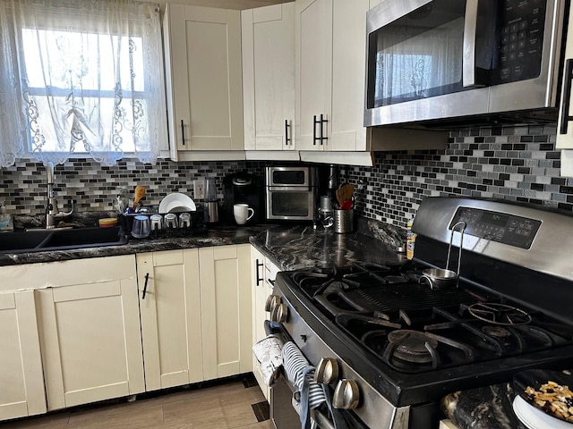 kitchen with decorative backsplash, appliances with stainless steel finishes, white cabinetry, and a sink