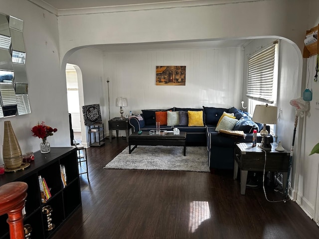 living room featuring arched walkways, crown molding, and dark wood-type flooring