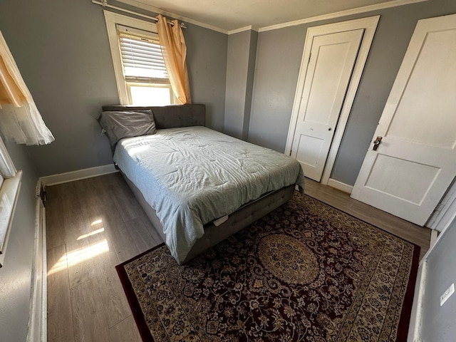 bedroom featuring baseboards, wood finished floors, and crown molding