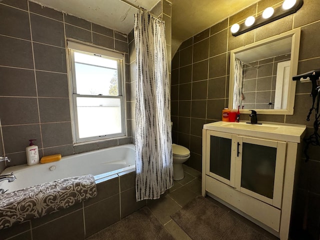 full bath with toilet, vanity, tile patterned floors, tile walls, and tiled shower / bath