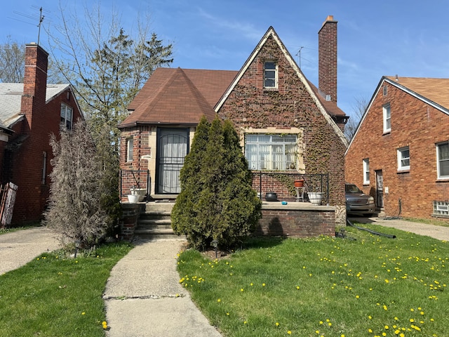 tudor house featuring a front yard and brick siding