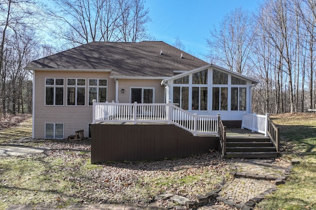 rear view of property featuring roof with shingles, a deck, and a sunroom