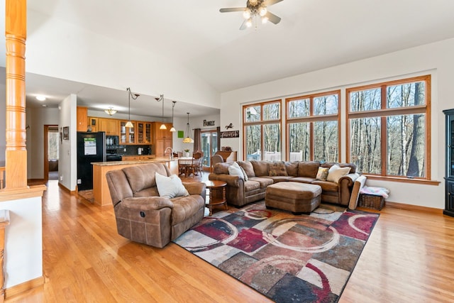 living room featuring lofted ceiling, light wood finished floors, decorative columns, baseboards, and ceiling fan