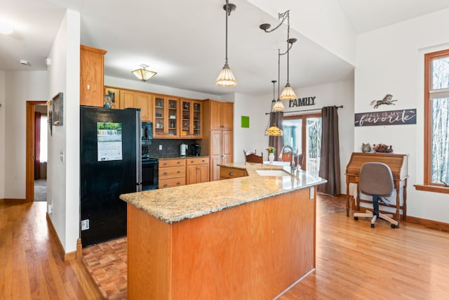 kitchen with tasteful backsplash, black appliances, light wood-style floors, and a sink