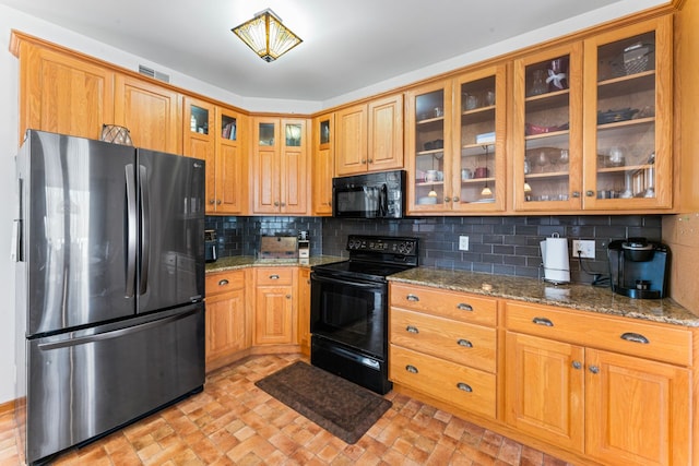 kitchen featuring visible vents, stone counters, black appliances, glass insert cabinets, and tasteful backsplash