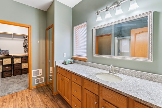 full bath featuring an enclosed shower, visible vents, vanity, and wood finished floors