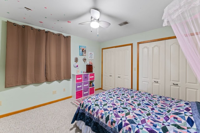 carpeted bedroom with visible vents, ceiling fan, two closets, and baseboards