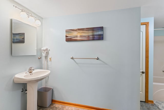 full bathroom featuring a tub, baseboards, and a sink