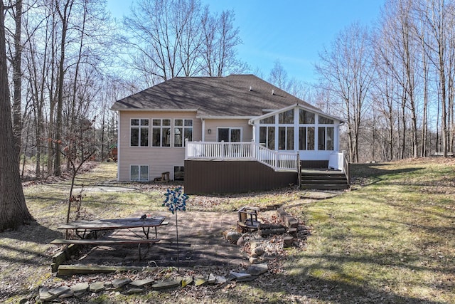 rear view of house featuring a shingled roof, a deck, and a sunroom