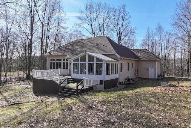 back of house featuring roof with shingles, a deck, and a sunroom