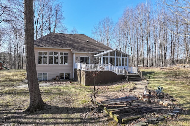 back of property with a wooden deck, a shingled roof, stairs, and a sunroom