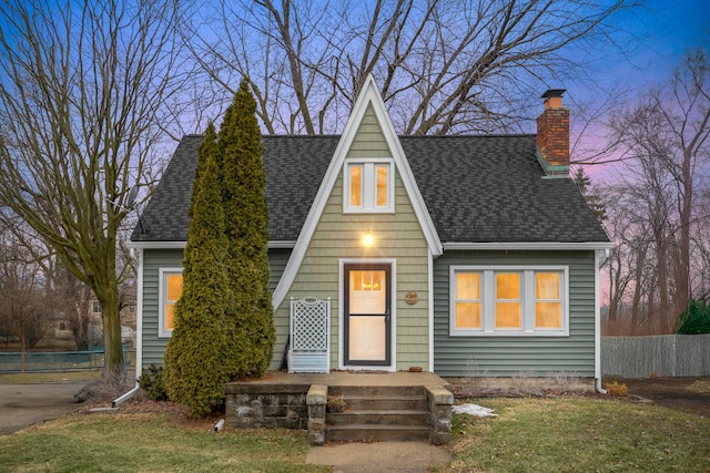 view of front of house featuring a chimney, a shingled roof, and fence