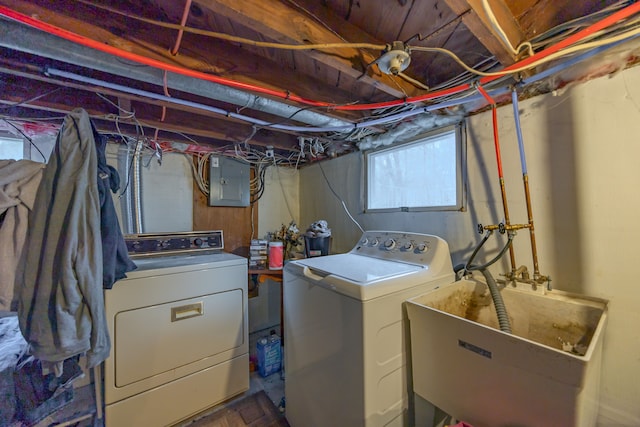 washroom featuring electric panel, laundry area, washing machine and dryer, and a sink