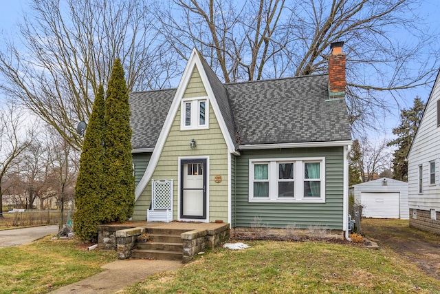 a-frame home with an outbuilding, driveway, a detached garage, roof with shingles, and a chimney