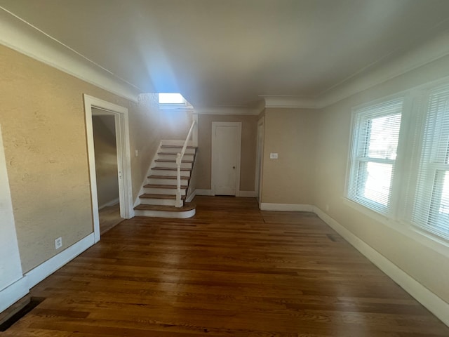 unfurnished living room with stairs, crown molding, wood finished floors, and baseboards