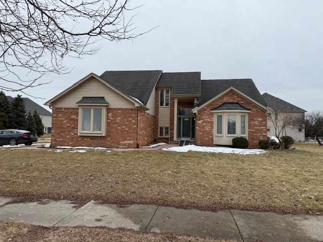 view of front facade with brick siding and a front lawn