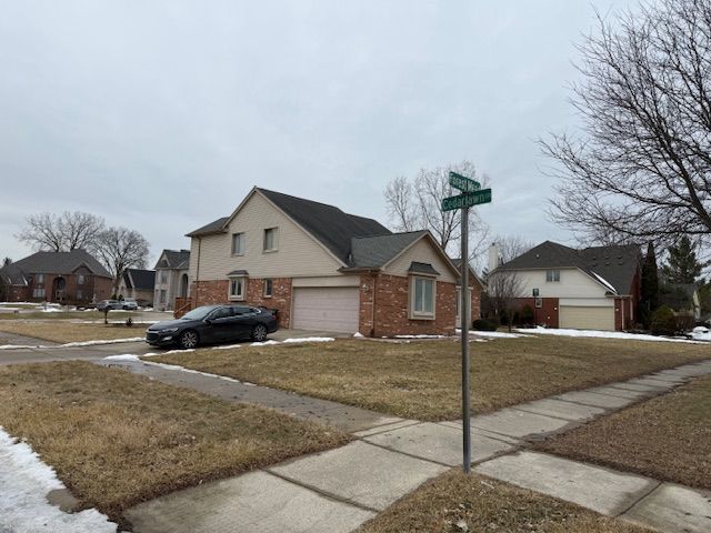 view of side of home featuring a yard, brick siding, a garage, and driveway