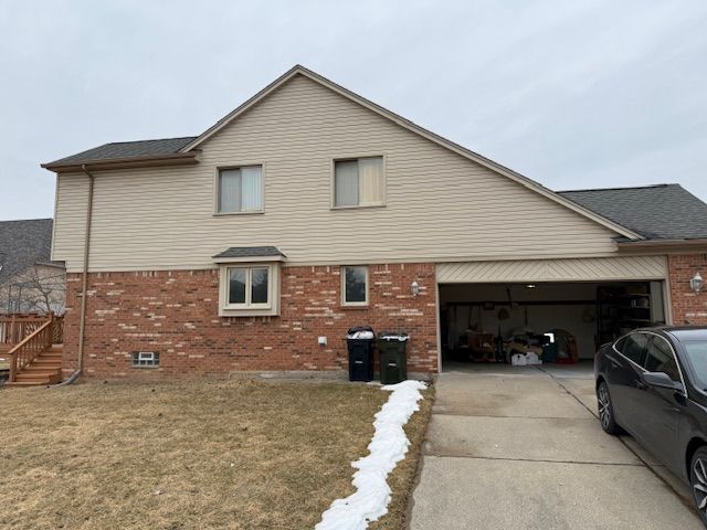 view of side of property featuring a garage, brick siding, and concrete driveway