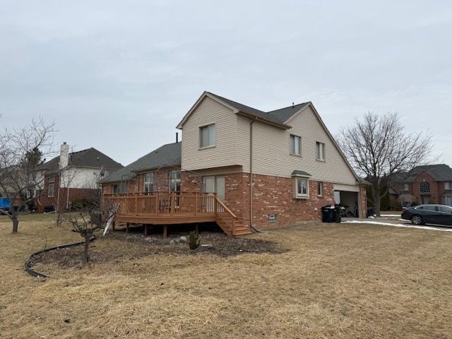 view of home's exterior with a wooden deck, brick siding, and a garage