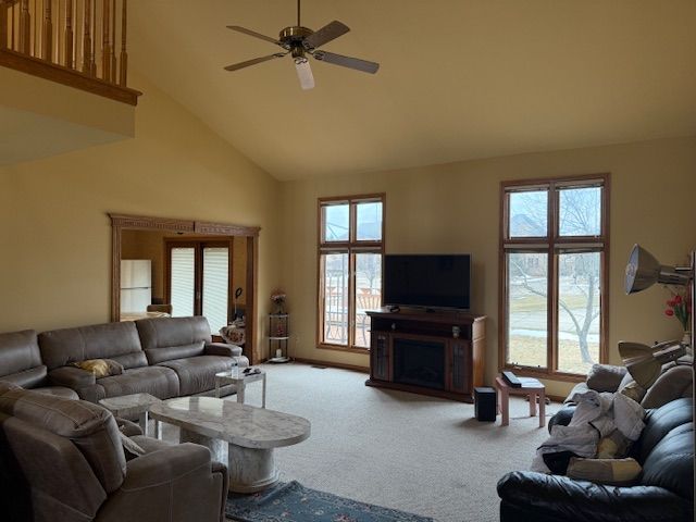 living area with carpet, ceiling fan, and high vaulted ceiling