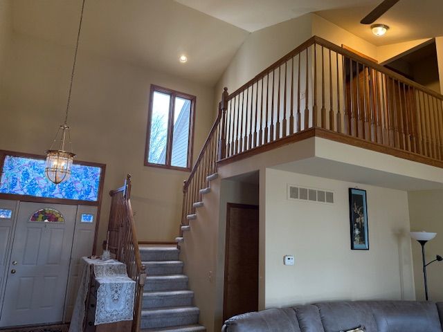 foyer featuring visible vents, high vaulted ceiling, stairs, and a notable chandelier