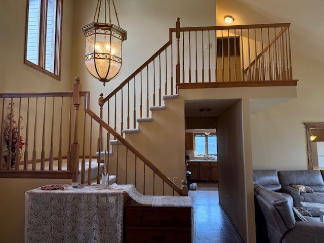 staircase featuring wood finished floors, a notable chandelier, and a towering ceiling