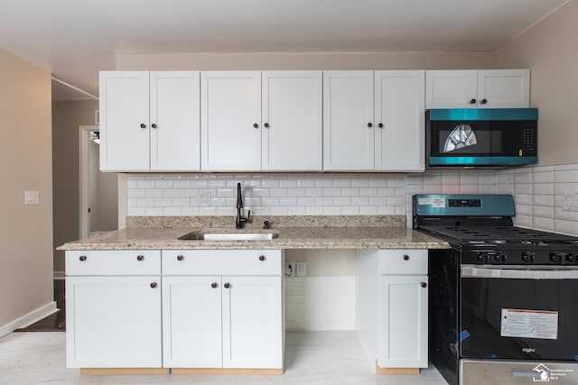 kitchen featuring a sink, light stone countertops, stainless steel gas range, and black microwave