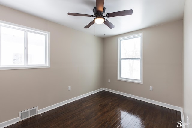 unfurnished room featuring visible vents, baseboards, dark wood-type flooring, and a ceiling fan