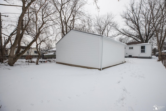 snow covered structure featuring an outdoor structure and fence