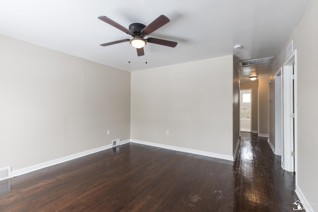 unfurnished room featuring visible vents, baseboards, attic access, and dark wood-style floors