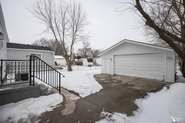 yard layered in snow featuring an outbuilding and a detached garage