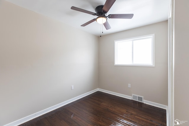 spare room with dark wood finished floors, visible vents, a ceiling fan, and baseboards