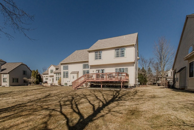 rear view of house featuring a deck, a shingled roof, and a yard