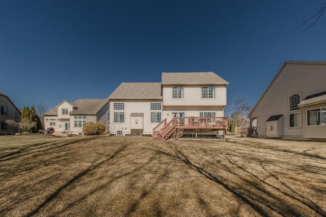 back of house featuring a lawn, roof with shingles, and a deck