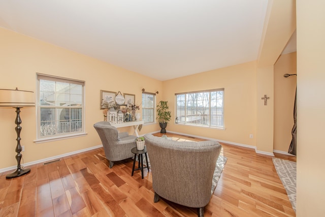 living room with wood finished floors, visible vents, and baseboards