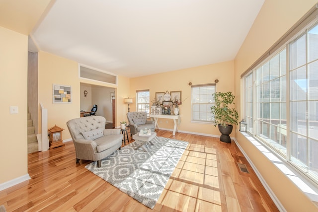 living room featuring stairway, light wood-style flooring, and baseboards