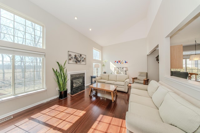 living room with wood finished floors, baseboards, visible vents, high vaulted ceiling, and a fireplace