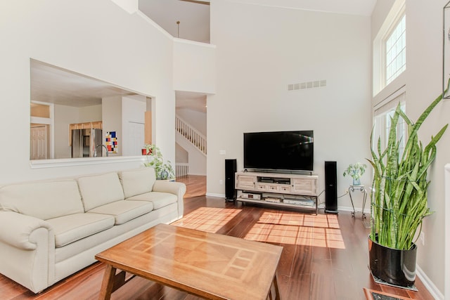 living area featuring visible vents, baseboards, wood finished floors, and stairway