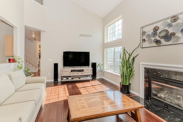 living area featuring visible vents, stairway, a fireplace, dark wood-style floors, and high vaulted ceiling