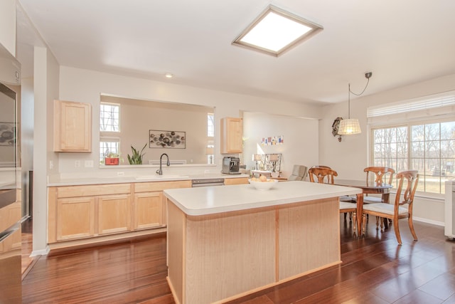 kitchen with dark wood-type flooring, light brown cabinetry, a sink, a kitchen island, and light countertops