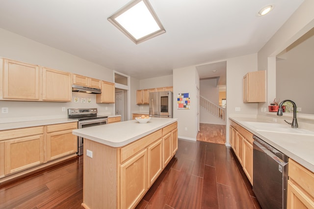 kitchen featuring under cabinet range hood, light brown cabinets, appliances with stainless steel finishes, and a sink