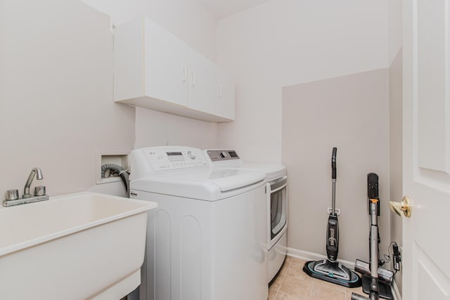 washroom with washing machine and clothes dryer, baseboards, light tile patterned flooring, cabinet space, and a sink