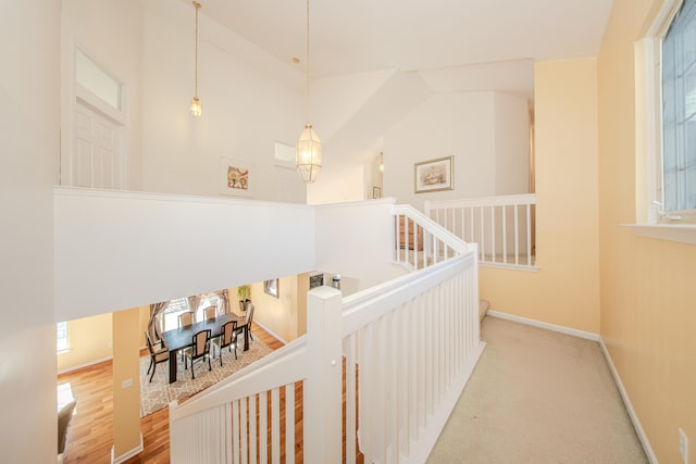 stairway with wood finished floors, baseboards, and a towering ceiling