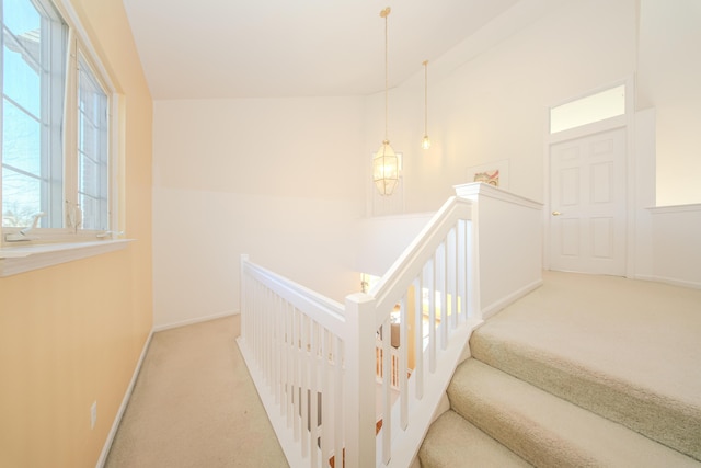 staircase featuring baseboards, carpet, and lofted ceiling