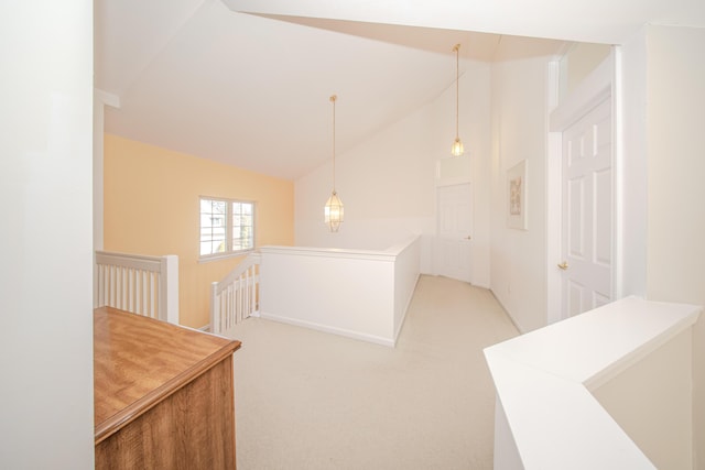 hallway with an upstairs landing, light carpet, and lofted ceiling