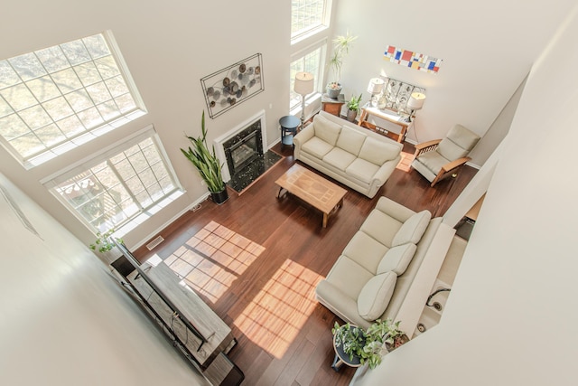 living room featuring wood finished floors, visible vents, a towering ceiling, and baseboards