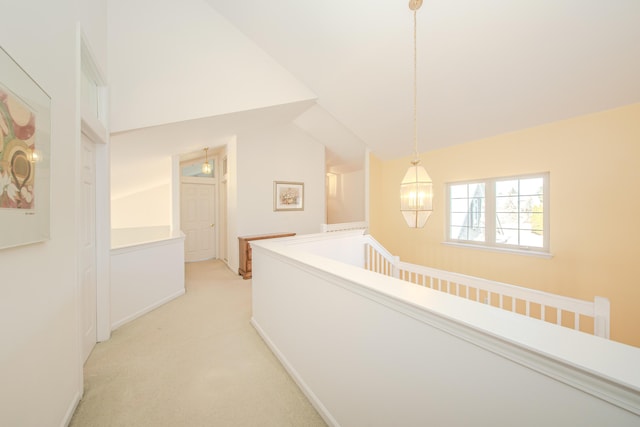 hallway with lofted ceiling and light colored carpet