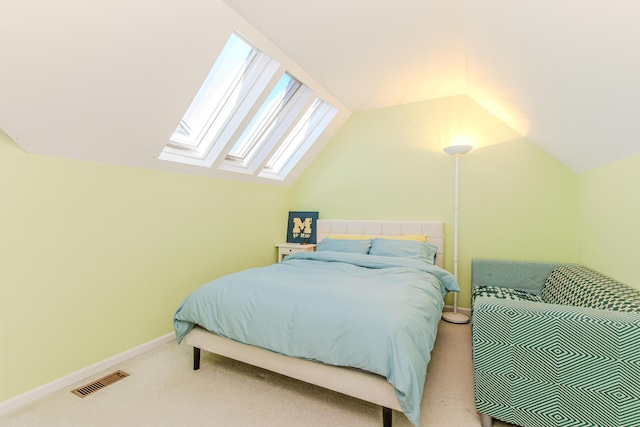 bedroom featuring lofted ceiling with skylight, carpet flooring, visible vents, and baseboards