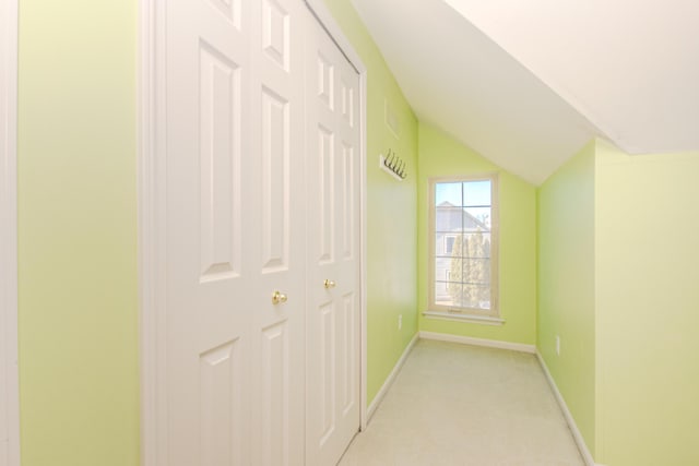 corridor featuring light carpet, baseboards, and vaulted ceiling