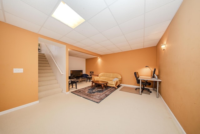 living area featuring stairway, a paneled ceiling, baseboards, and carpet floors